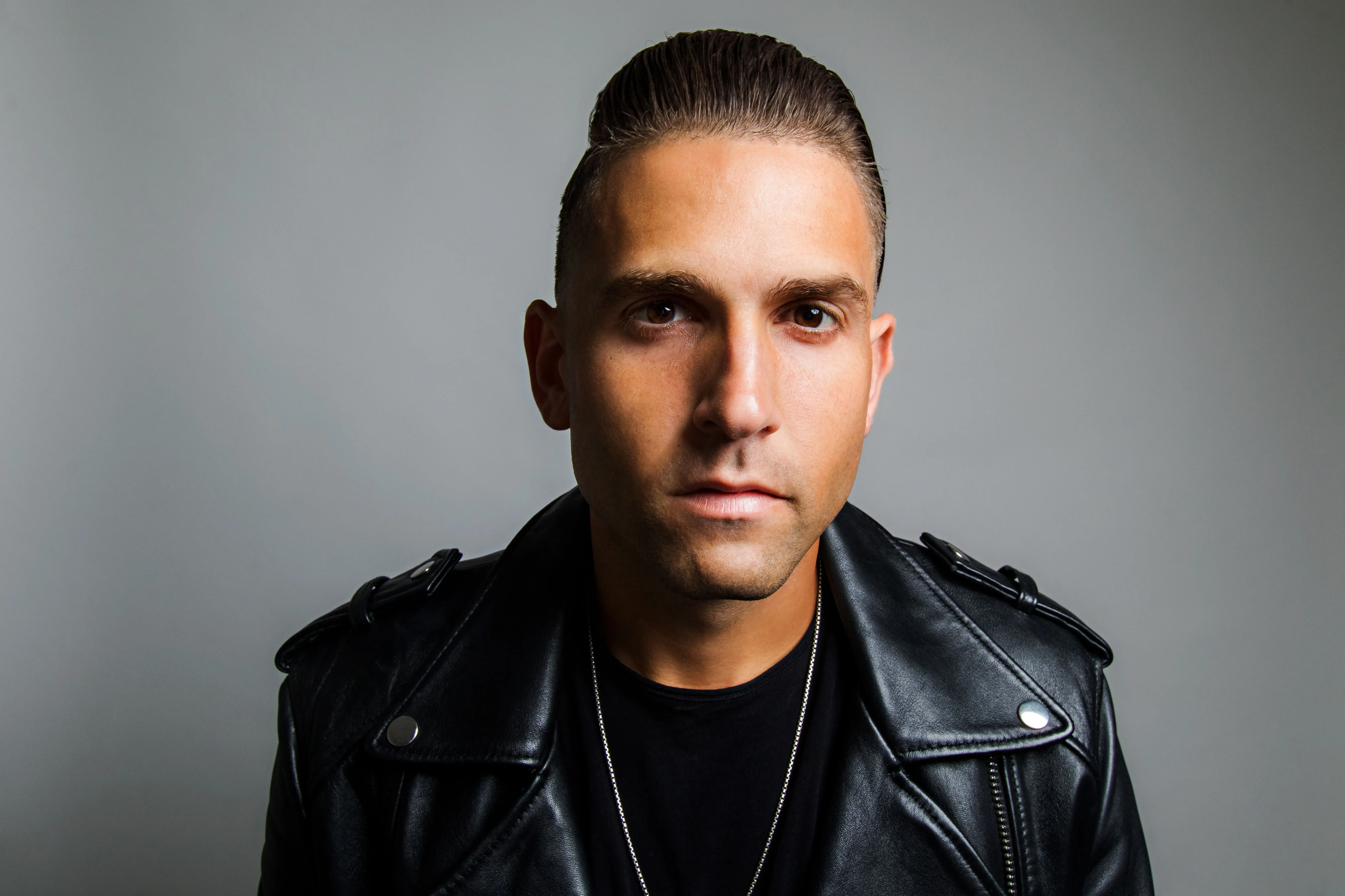 Chris Valencia facing the camera in a black leather jacket.