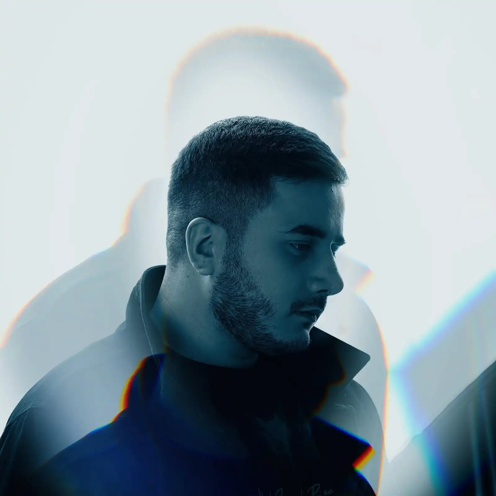 Hafex in profile, looking down, in a blue-toned double-exposure portrait.